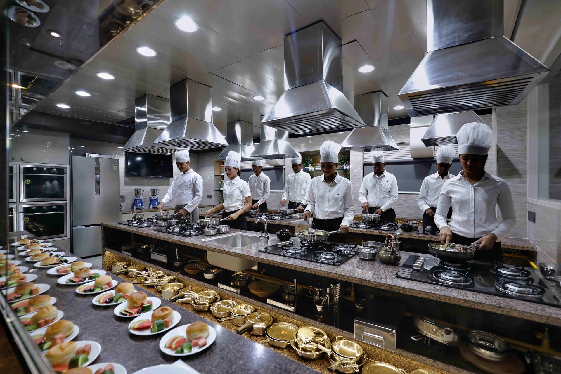 Culinary students working a brigade line inside the Wings commercial kitchen lab