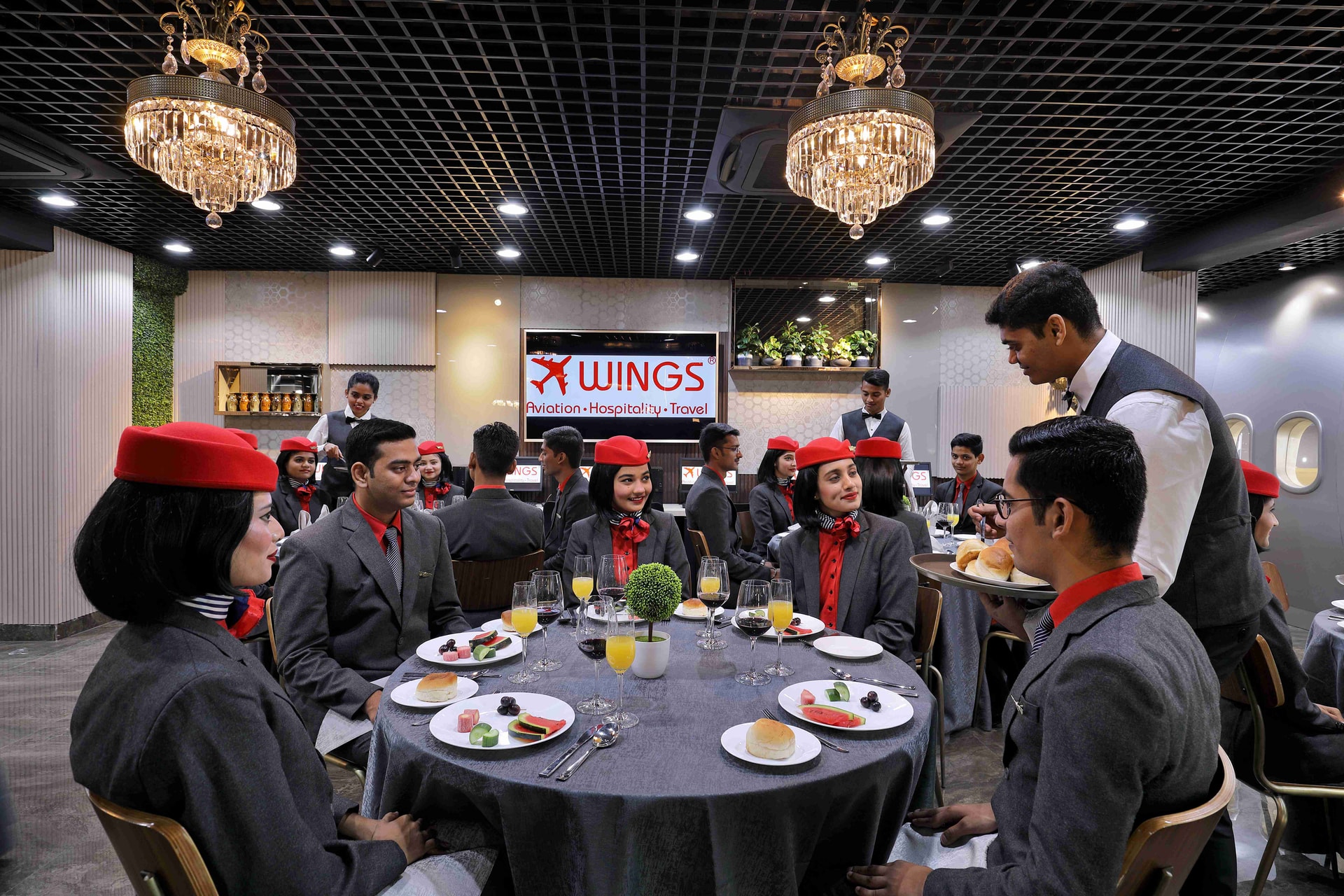 Hospitality students learning fine-dining silver service at Wings Institute mock restaurant Gujarat
